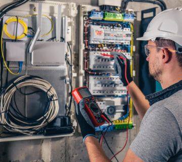 Man electrical technician working switchboard with fuses 360x320